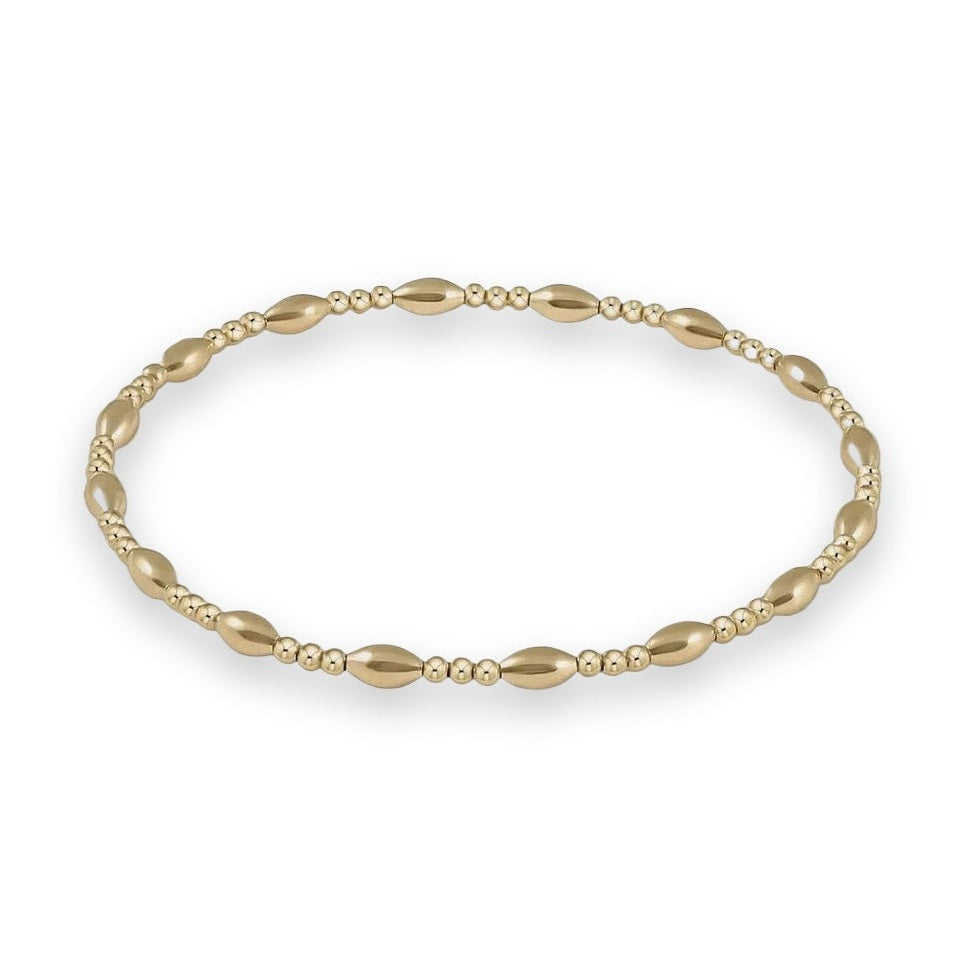 Polished yellow gold jewelry bracelet featuring an alternating pattern of smooth elongated marquise-shaped beads and trios of small spherical beads with a reflective mirror finish against a minimalist gray background