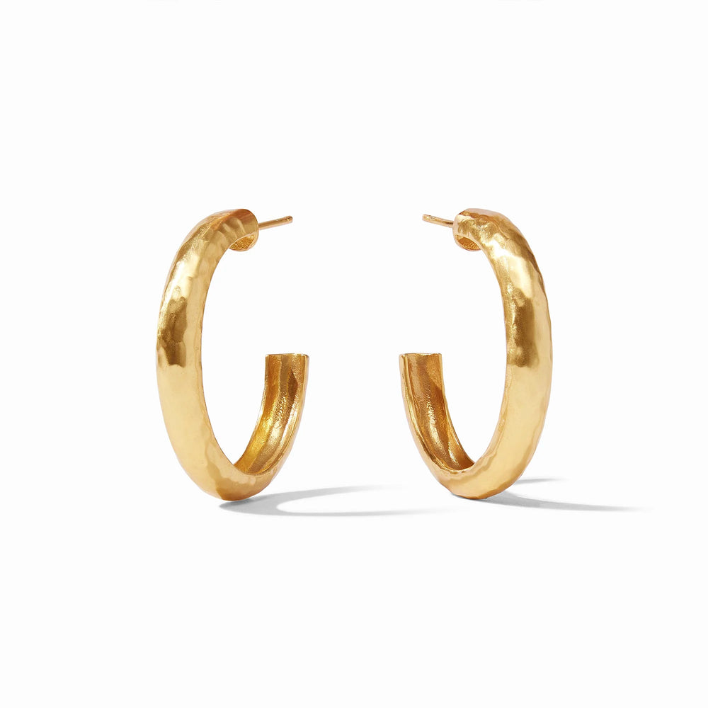 Gold-plated brass earrings featuring a pair of thick C-shaped hoops on a minimalist white background with a distinctive hammered surface and a high-shine golden luster