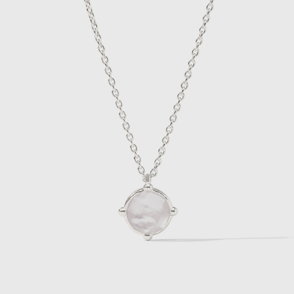 Sterling silver jewelry piece featuring a round iridescent white gemstone pendant centered on a light gray background with a delicate cable chain and unique four-prong compass settings