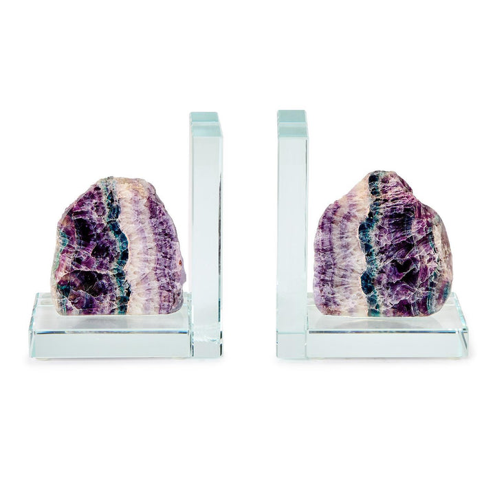 Crystal and fluorite stone bookends on a white background featuring vibrant purple and teal mineral banding, transparent L-shaped glass bases, and raw natural textures