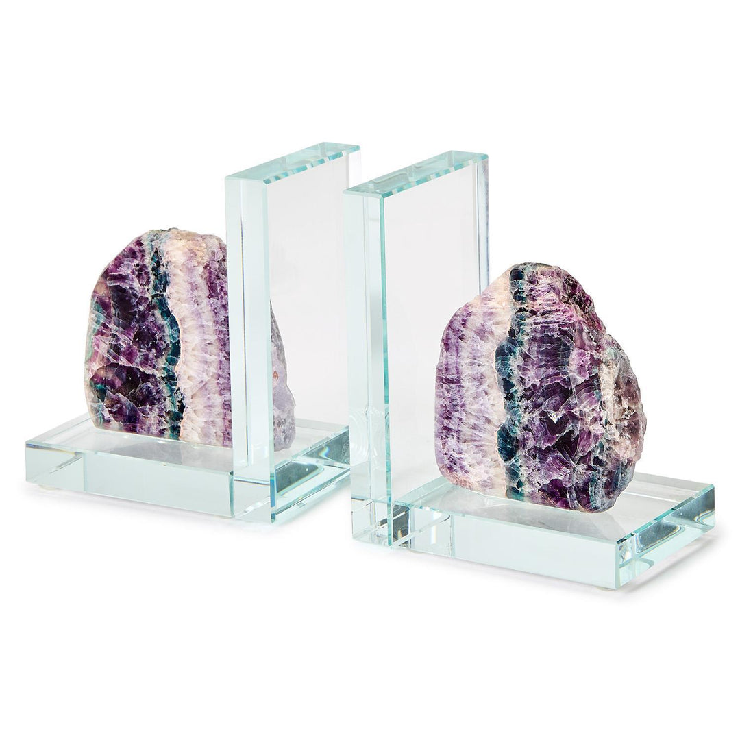 Glass and fluorite stone bookends featuring raw-edged crystal geodes with vibrant purple and teal banding mounted on transparent L-shaped glass bases against a plain white background