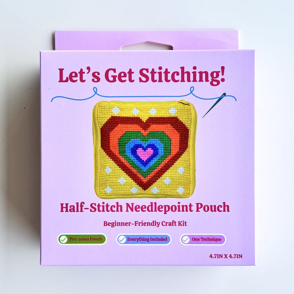 A boxed craft kit labeled "Let's Get Stitching!" and "Half-Stitch Needlepoint Pouch" on a plain white background. The package is light purple with a central illustration of a multicolored heart-shaped needlepoint patch.