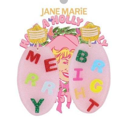 Acrylic dangle earrings by Jane Marie feature pink oval pendants with colorful glitter letters spelling MERRY and BRIGHT hanging from gold glitter studs on a card with an iconic Dolly Parton illustration