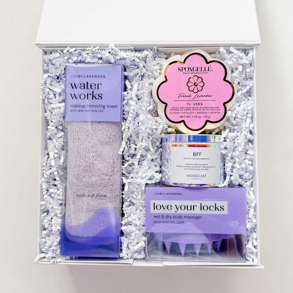 Set of hair care products including a bottle, a jar, and a brush in a decorative box on a white background.