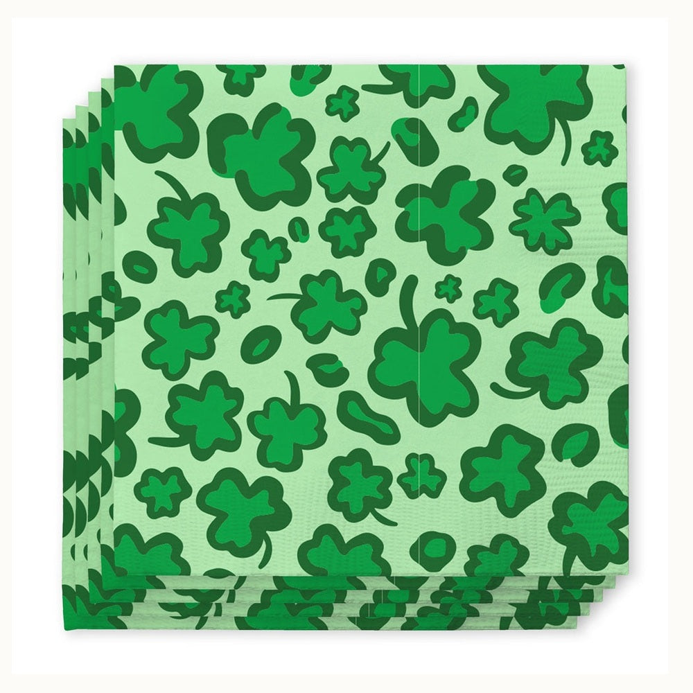 Paper napkins featuring a repeating St. Patrick's Day pattern of iconic dark green shamrocks in various sizes and organic shapes across a light mint green background with a subtle paper texture