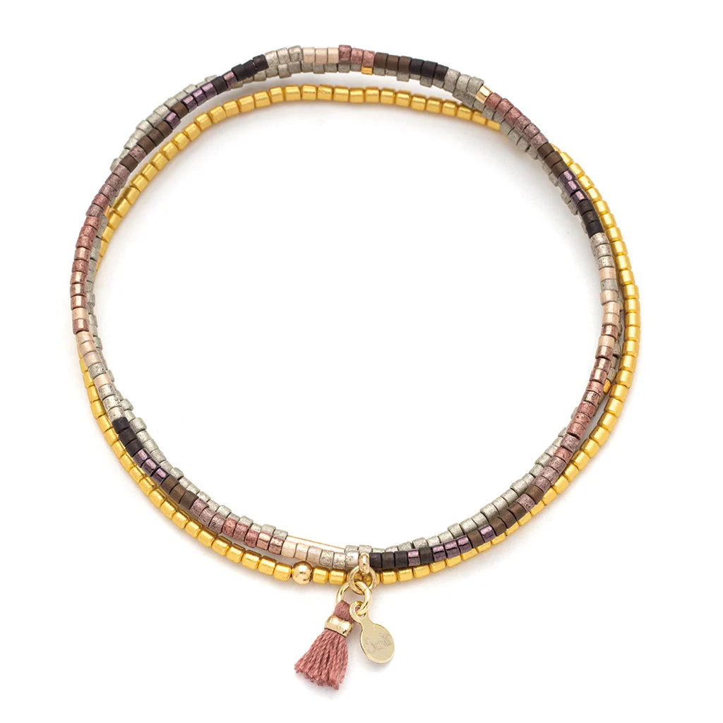 Handcrafted beaded wrap bracelet by Scout Curated Wear featuring circular strands of metallic earth-toned beads on a white background with a delicate dusty rose tassel and a small gold logo tag