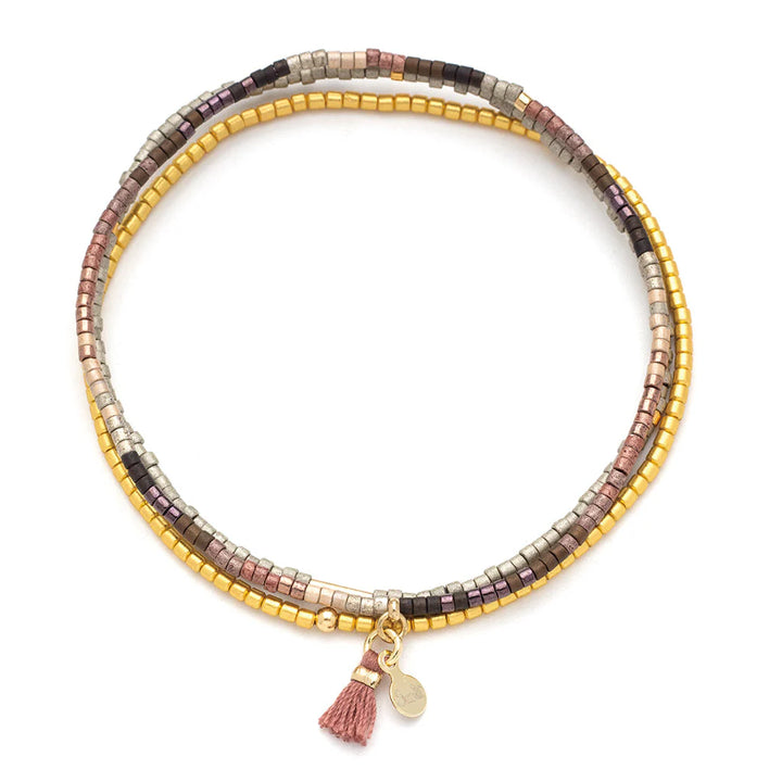 Handcrafted beaded wrap bracelet by Scout Curated Wear featuring circular strands of metallic earth-toned beads on a white background with a delicate dusty rose tassel and a small gold logo tag