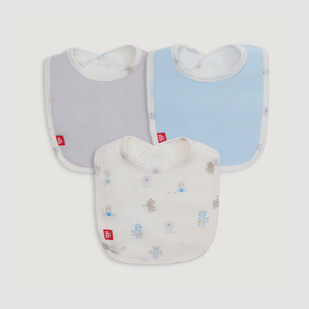 Product photograph of Mothercare baby bibs featuring solid grey and light blue designs alongside a white bib decorated with whimsical animal illustrations and signature red brand tags against a neutral background