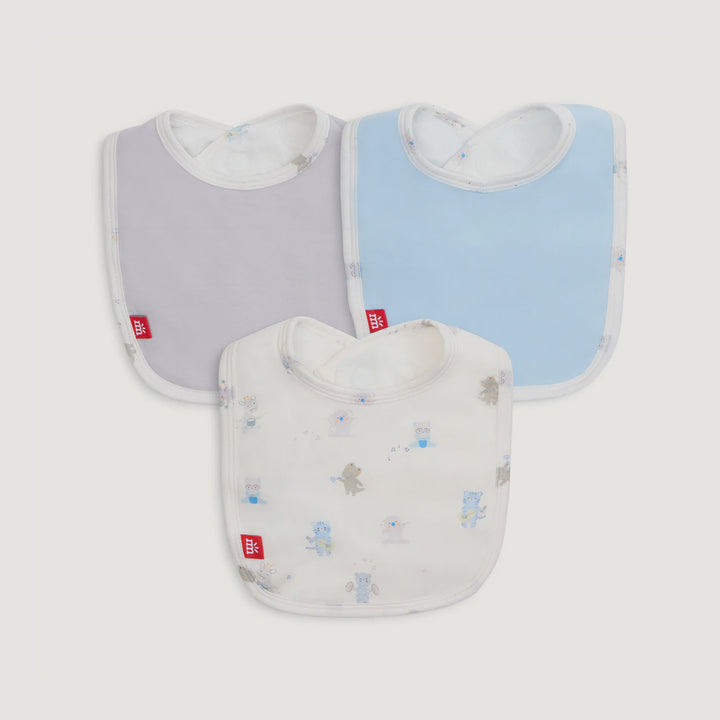 Product photograph of Mothercare baby bibs featuring solid grey and light blue designs alongside a white bib decorated with whimsical animal illustrations and signature red brand tags against a neutral background