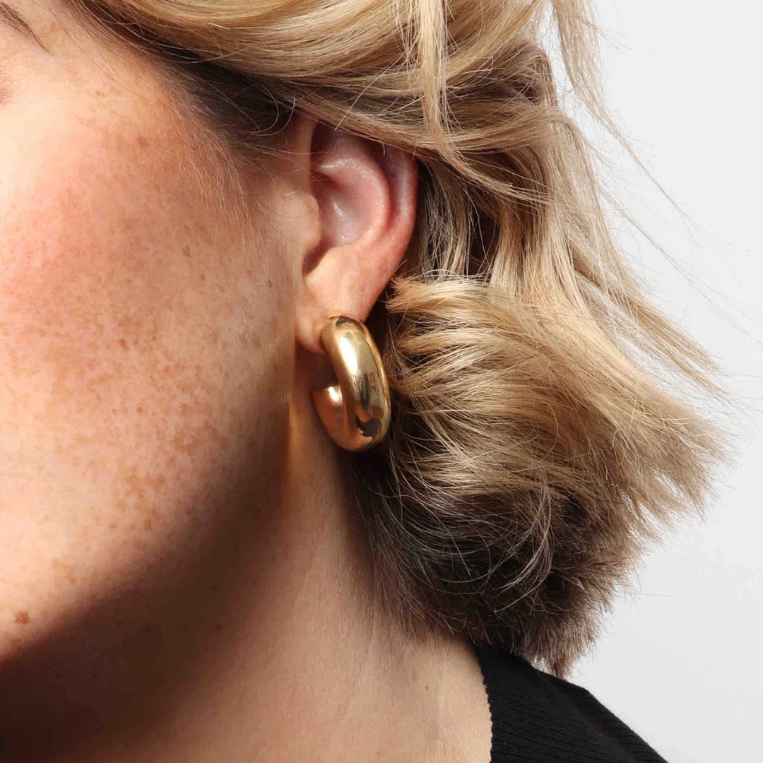 Gold hoop earring worn by a person with blonde hair.