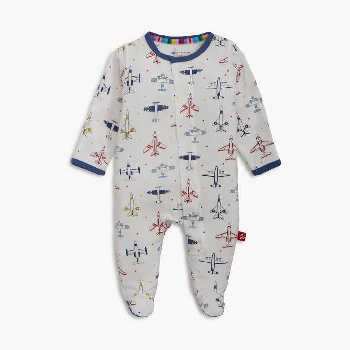 Organic cotton baby sleepsuit by Magnetic Me featuring a white footed onesie patterned with colorful vintage airplanes and tiny stars, accented by navy blue trim and a rainbow-striped inner neckline