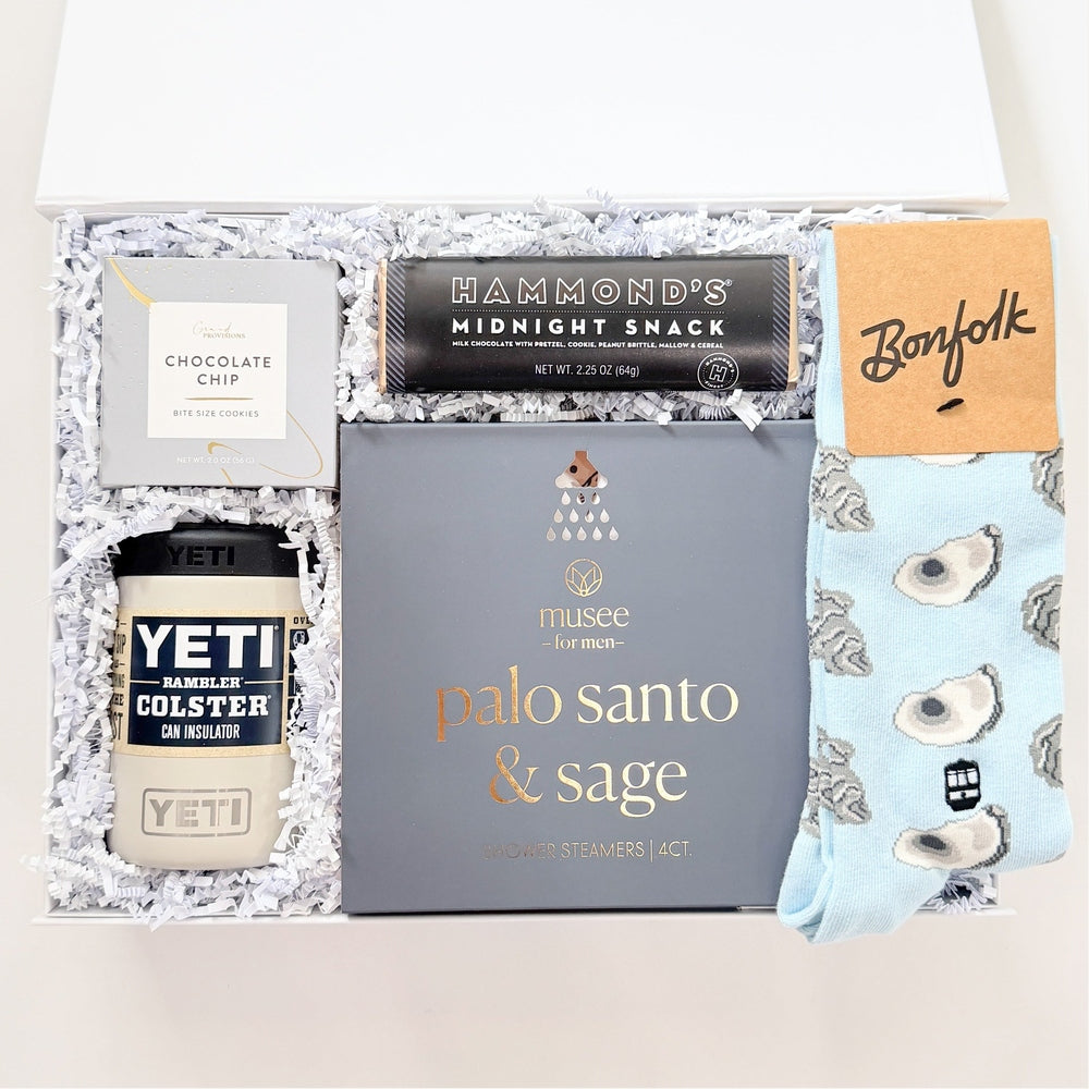 Gift box with various items including a Yeti cup, Palo Santo & Sage box, and other products on a white background.
