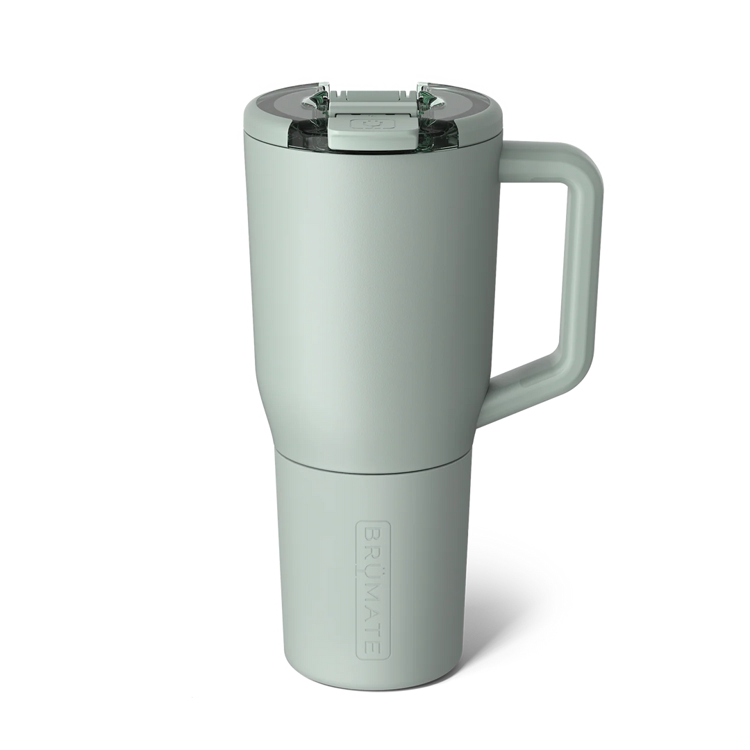 Product photograph by BrüMate of a sage green Era insulated tumbler against a white background featuring a clear rotatable locking lid, a large ergonomic handle, and a matte finish with an embossed brand logo at the base