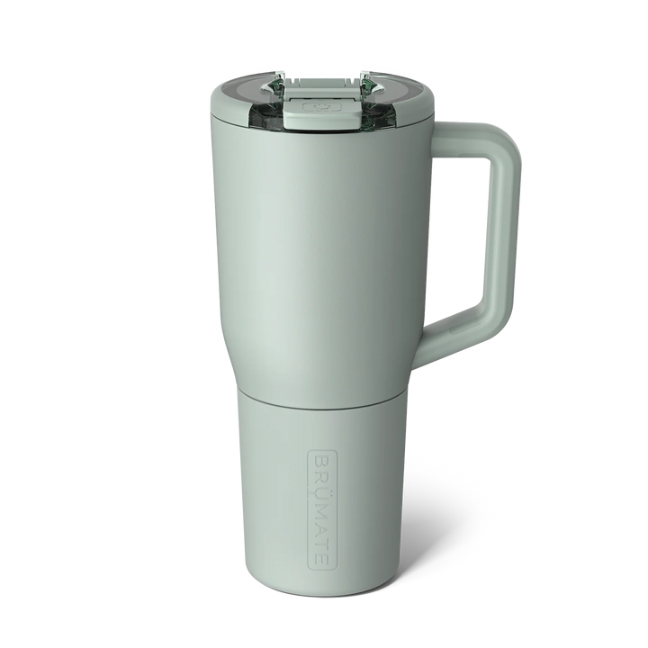 Product photograph by BrüMate of a sage green Era insulated tumbler against a white background featuring a clear rotatable locking lid, a large ergonomic handle, and a matte finish with an embossed brand logo at the base