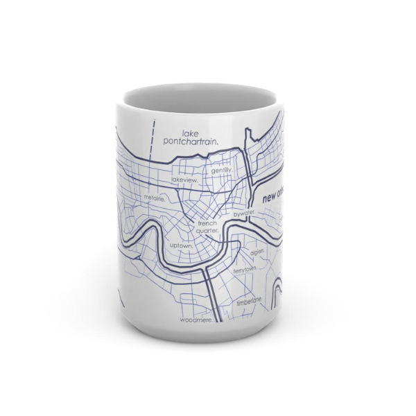 White ceramic mug featuring a minimalist blue ink street map of New Orleans including the French Quarter and Lake Pontchartrain with delicate line work and lowercase labels for local neighborhoods like Uptown and Metairie