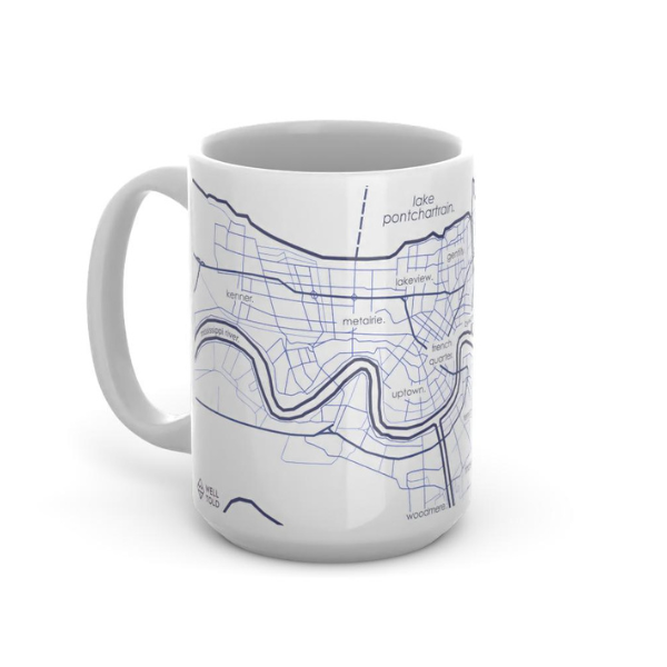 White ceramic mug by Well Told featuring a blue line-art map of New Orleans including the winding Mississippi River and Lake Pontchartrain with minimalist labels for the French Quarter and Uptown in lowercase typography