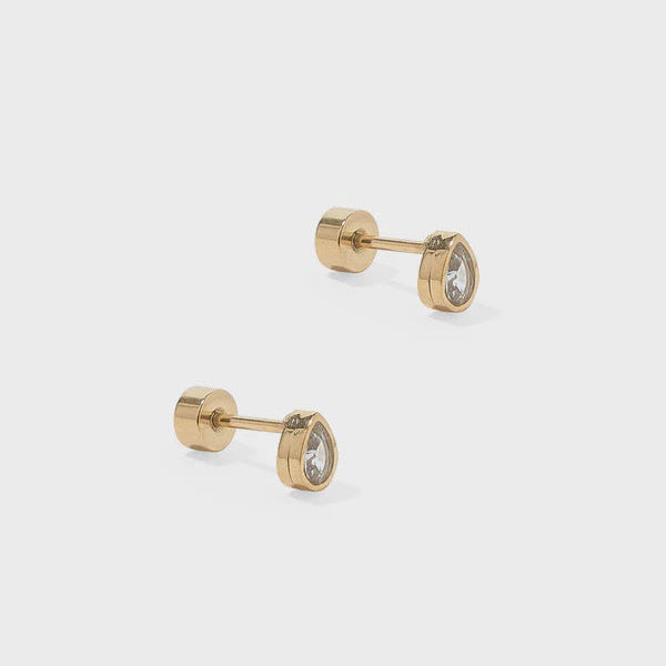 Professional product photograph of yellow gold stud earrings featuring teardrop-shaped clear crystals in bezel settings and secure flat-back posts on a neutral light grey background
