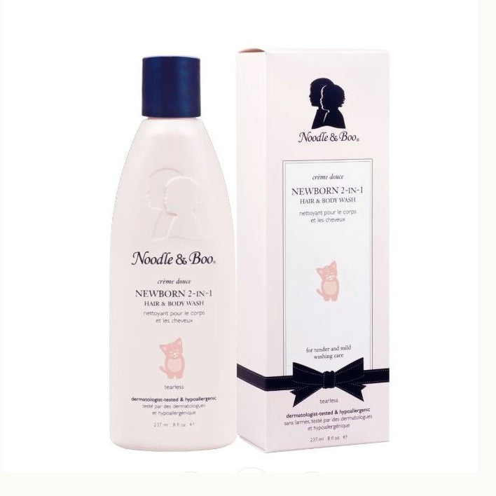Product photograph for Noodle & Boo featuring the Newborn 2-in-1 Hair & Body Wash in a pale pink bottle with a navy blue cap alongside a white box adorned with the brand’s iconic silhouette and a decorative black ribbon bow