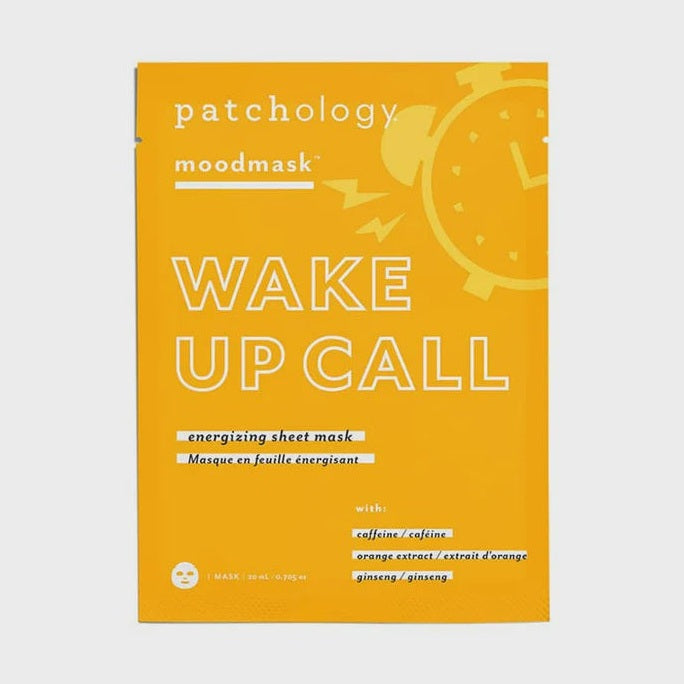 Product packaging design by Patchology featuring a bright yellow Wake Up Call moodmask sachet centered in a studio setting, showcasing a white alarm clock graphic with lightning bolts and text labels for caffeine, orange extract, and ginseng