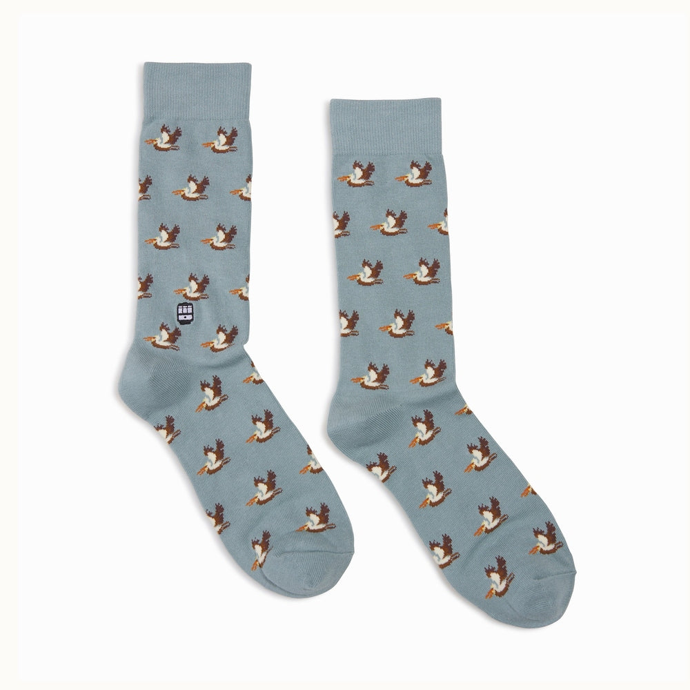 Knit crew socks featuring a San Francisco theme with a repeating pattern of brown and white pelicans with orange beaks on a light blue background and a small iconic cable car emblem