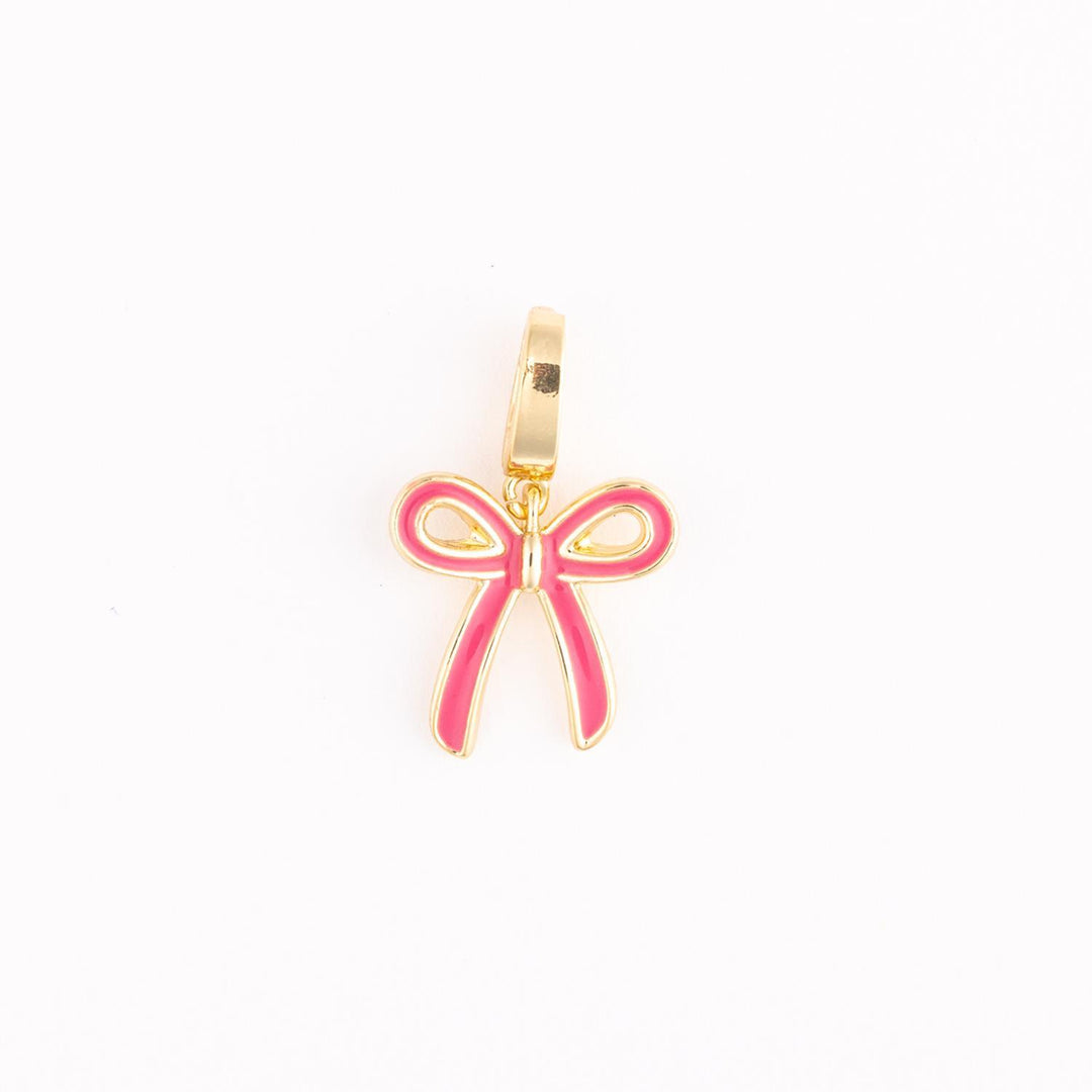 Gold-plated enamel jewelry featuring a pink ribbon bow charm centered on a white background with a polished gold hanging bail and vibrant fuchsia inlay detailing