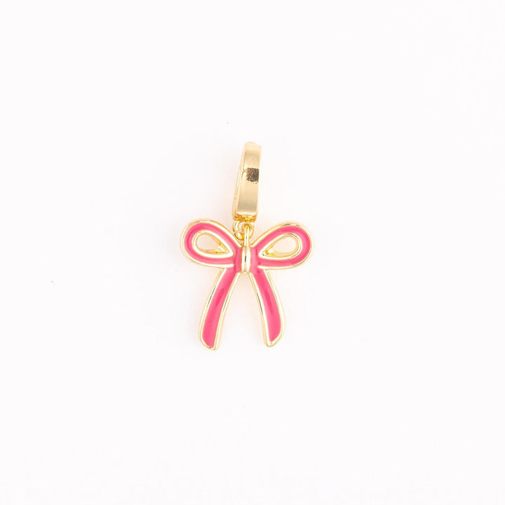 Gold-plated enamel jewelry featuring a pink ribbon bow charm centered on a white background with a polished gold hanging bail and vibrant fuchsia inlay detailing