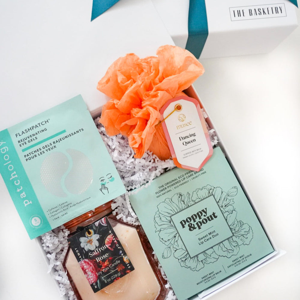 Gift set with bath products and a teal ribbon on a white background