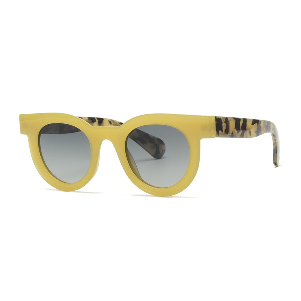 Product photograph of chunky round sunglasses on a white studio backdrop featuring a pale yellow matte frame, gray gradient lenses, and tortoiseshell patterned arms