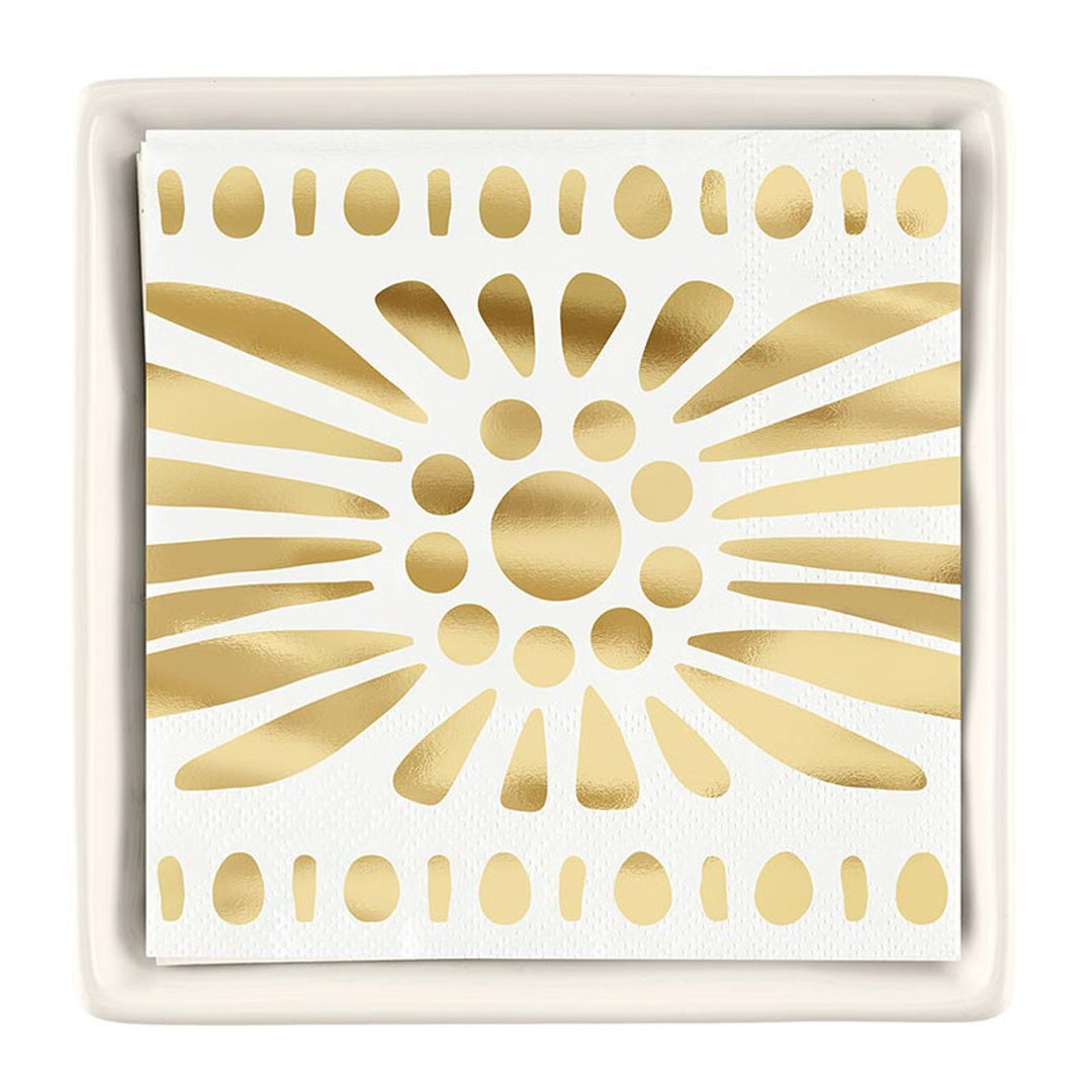 Paper and ceramic tabletop accessory featuring a gold foil sunburst napkin inside a white square tray with a central metallic burst design and horizontal rows of golden dots