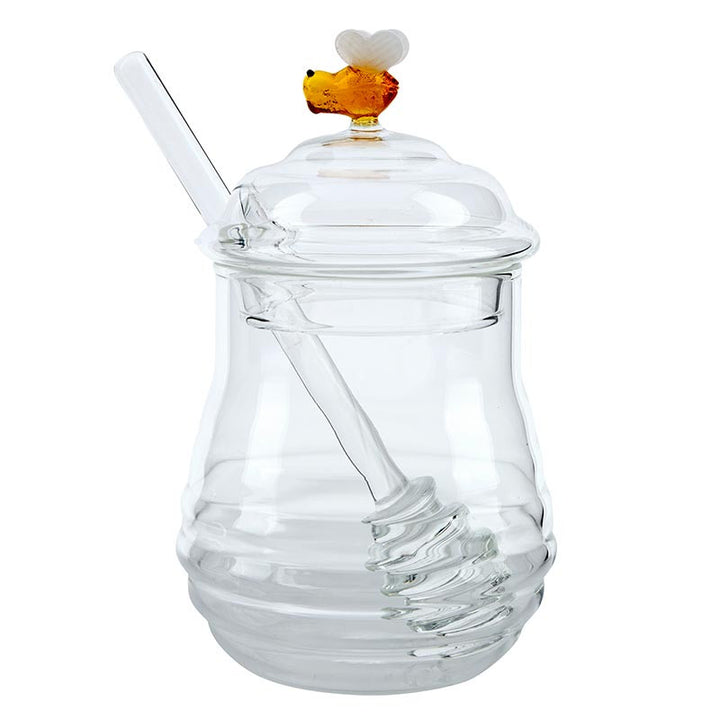 Hand-blown borosilicate glass honey jar by Ichendorf Milano featuring a clear ribbed beehive-shaped body and a lid topped with a tiny amber glass bee with white wings and an included clear glass honey dipper