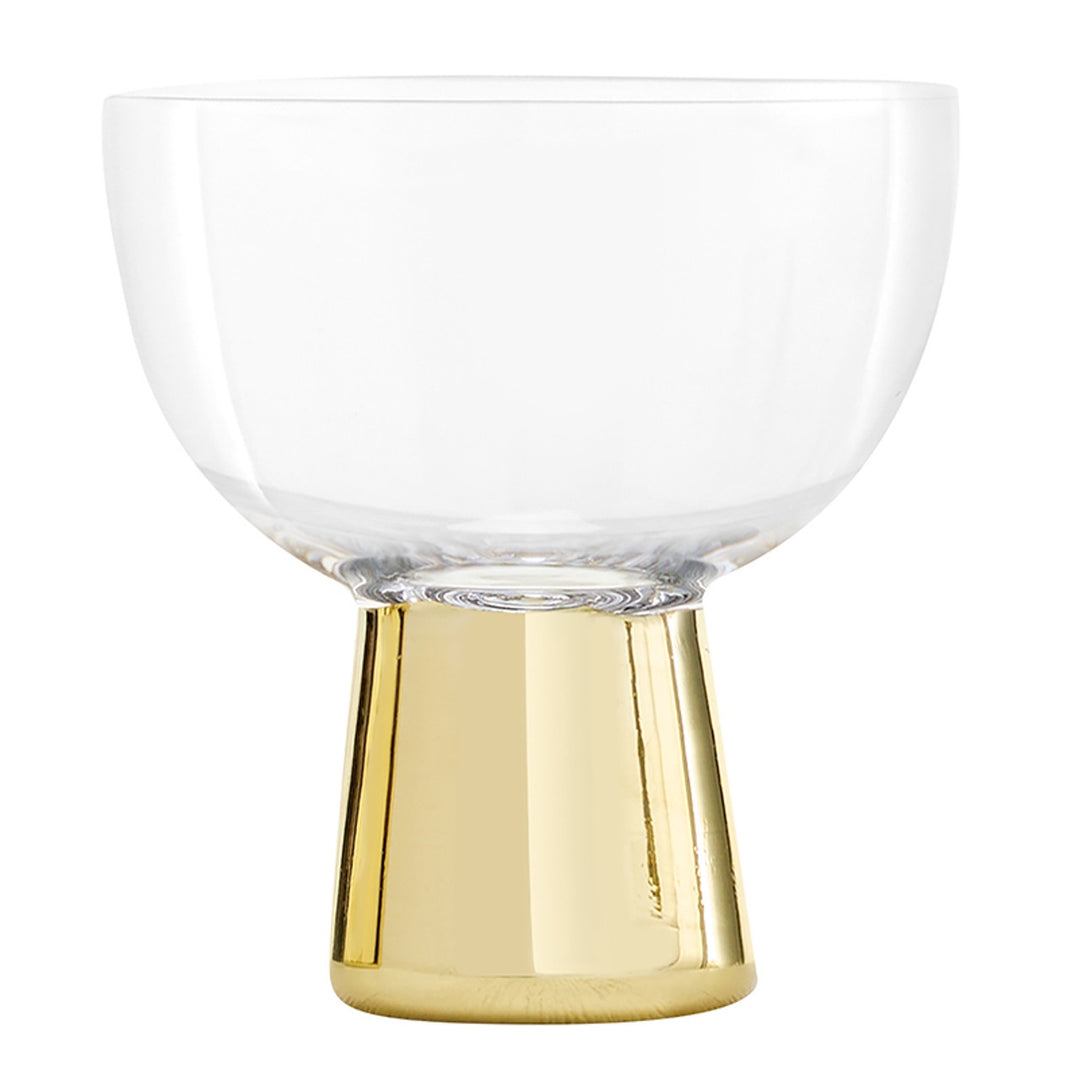 Mouth-blown glass and polished brass-finish coupe glass by Tom Dixon featuring a wide clear bowl and an iconic heavy tapered gold-plated base with a reflective high-shine surface against a white background