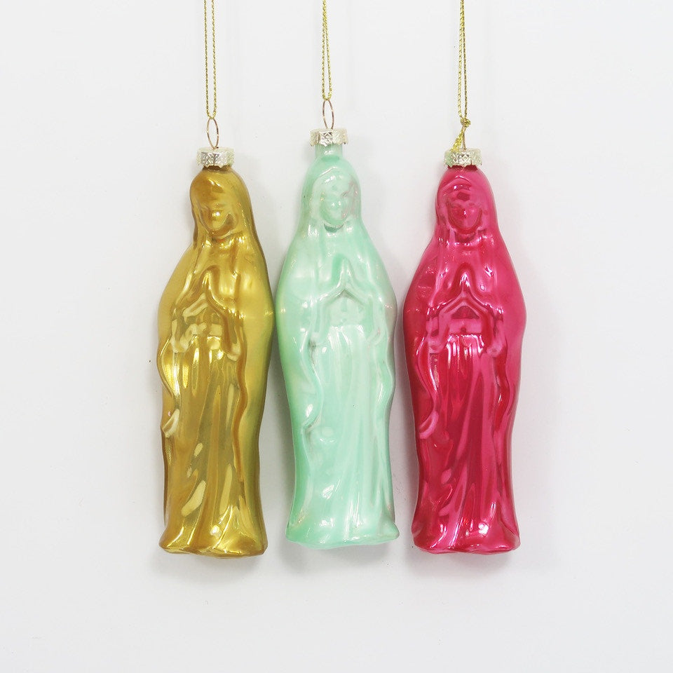 Molded glass ornaments of the Virgin Mary hanging against a white background in metallic gold, mint green, and hot pink with reflective glossy finishes and silver caps