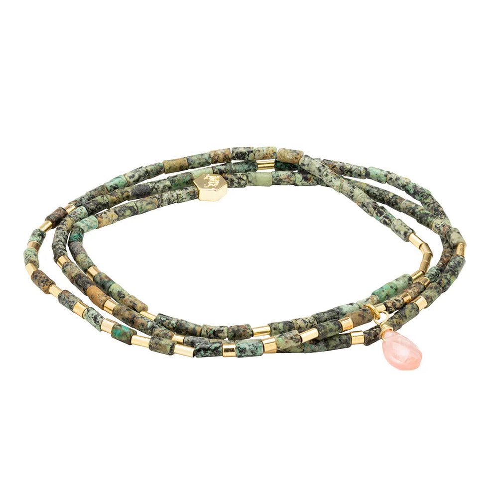 Beaded jewelry by Scout Curated Wear featuring a triple-wrap bracelet of mottled green African turquoise tube beads on a white background with a faceted pink rose quartz teardrop and a small hexagonal gold logo charm