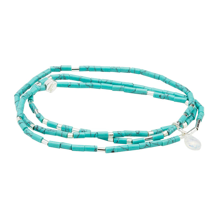 Handcrafted jewelry by Scout Curated Wears featuring a triple-wrap bracelet of cylindrical turquoise beads with dark veining, intermittent silver metallic spacers, and a faceted iridescent moonstone charm on a white background