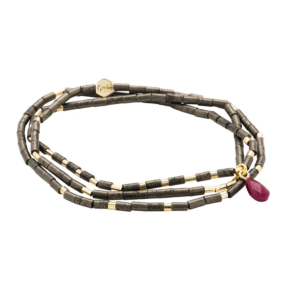 Handcrafted Scosha jewelry featuring a triple-strand wrap bracelet made of matte grey tube beads with polished gold spacers and a faceted raspberry pink ruby teardrop charm on a plain white background