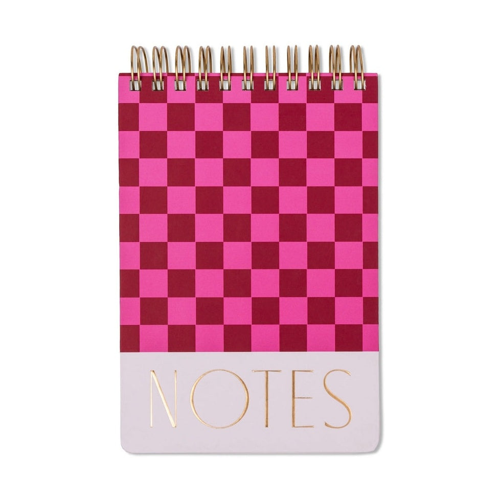 Stationery notebook featuring a vibrant hot pink and burgundy checkerboard design centered on a white background with metallic gold foil NOTES typography on a light pink bottom border and a gold-tone wire-o spiral binding at the top