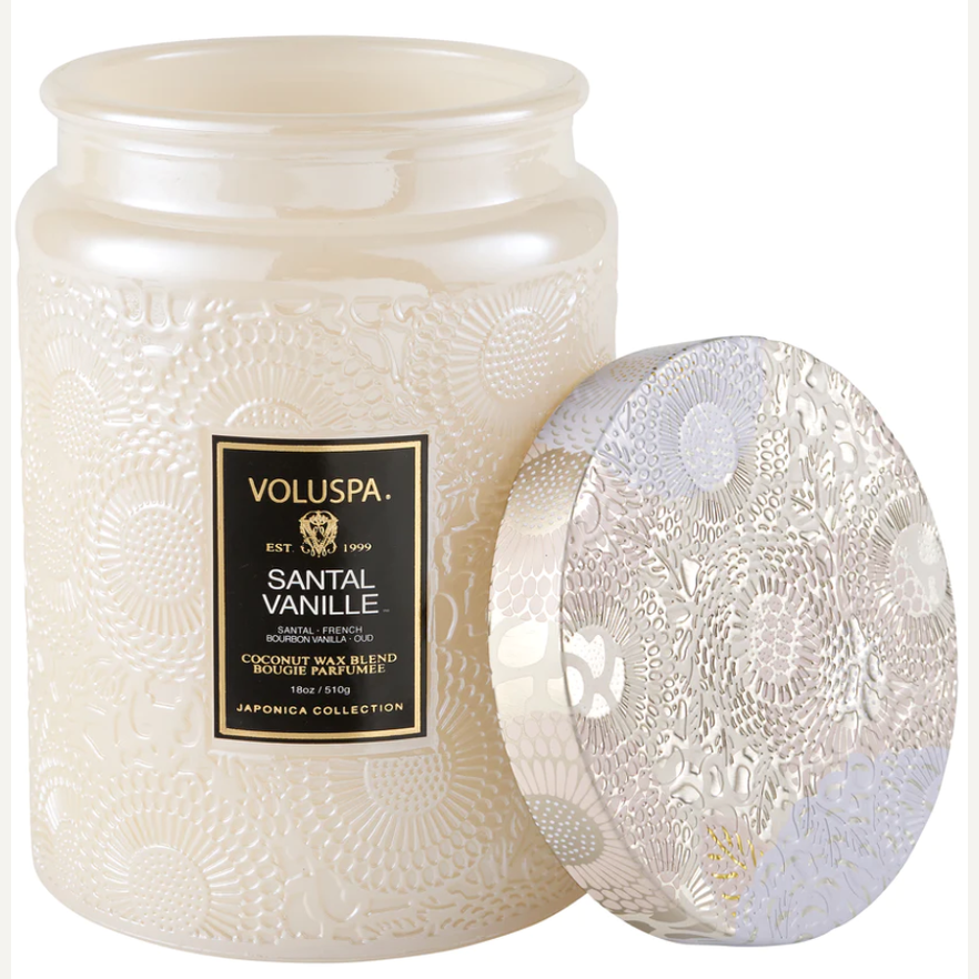 Scented candle by Voluspa featuring the Santal Vanille fragrance in an iridescent pearlescent glass jar with a raised floral Japonica pattern and a black label with gold lettering set against a white background