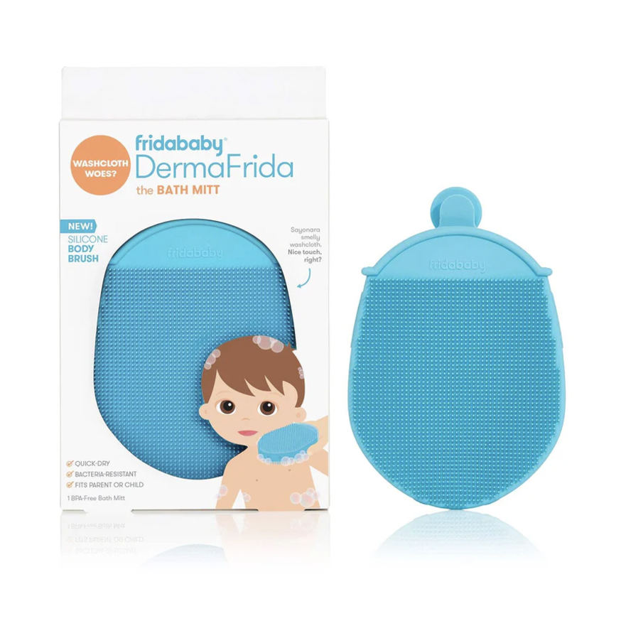 Commercial product photography by Fridababy featuring the light blue DermaFrida silicone bath mitt and its packaging on a white reflective surface with soft textured bristles, a built-in suction cup handle, and a cartoon illustration of a child with soap bubbles