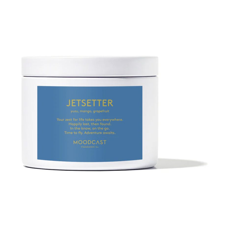 Studio photograph by Moodcast Fragrance Co of the Jetsetter scented candle featuring a white jar with a slate blue label, gold-toned typography, and a subtle cast shadow on a minimalist white background