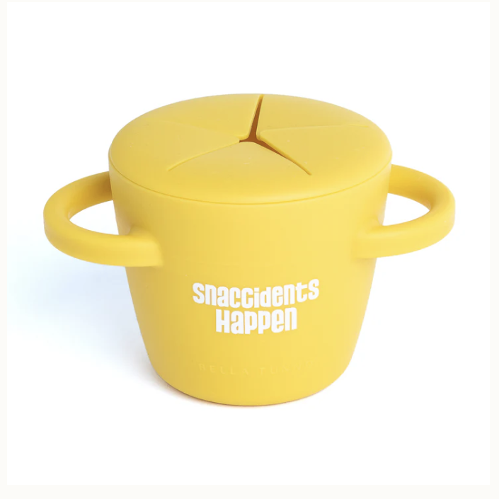 Product photograph by Bella Tunno of a yellow silicone toddler snack cup on a white background featuring the white text Snaccidents Happen with two curved side handles and a flexible star-slit lid