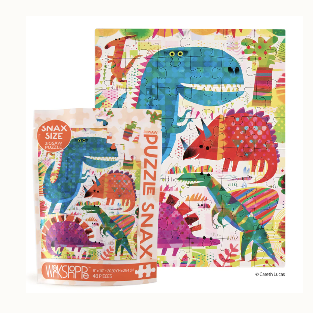 Jigsaw puzzle by Gareth Lucas depicts a vibrant prehistoric landscape with a large blue polka-dot Tyrannosaurus Rex, a red geometric Triceratops, and colorful abstract trees shown next to its 48-piece Snax size packaging