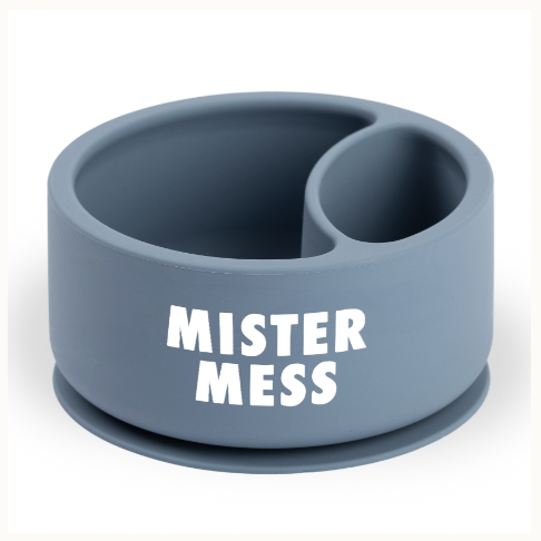 Silicone baby bowl by Mister Mess showcases a matte dusty blue divided feeding dish on a white background featuring a round suction base and bold white block lettering