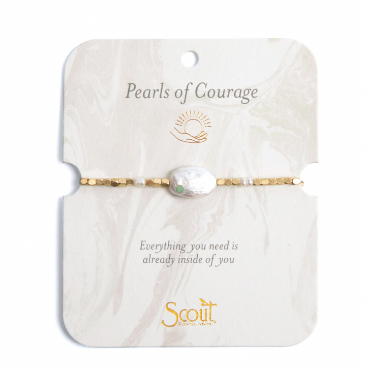 Jewelry by Scout Curated Wears featuring a Pearls of Courage bracelet centered on a marble-patterned card, showcasing a large iridescent baroque pearl with a tiny green inset stone and gold-toned faceted beads