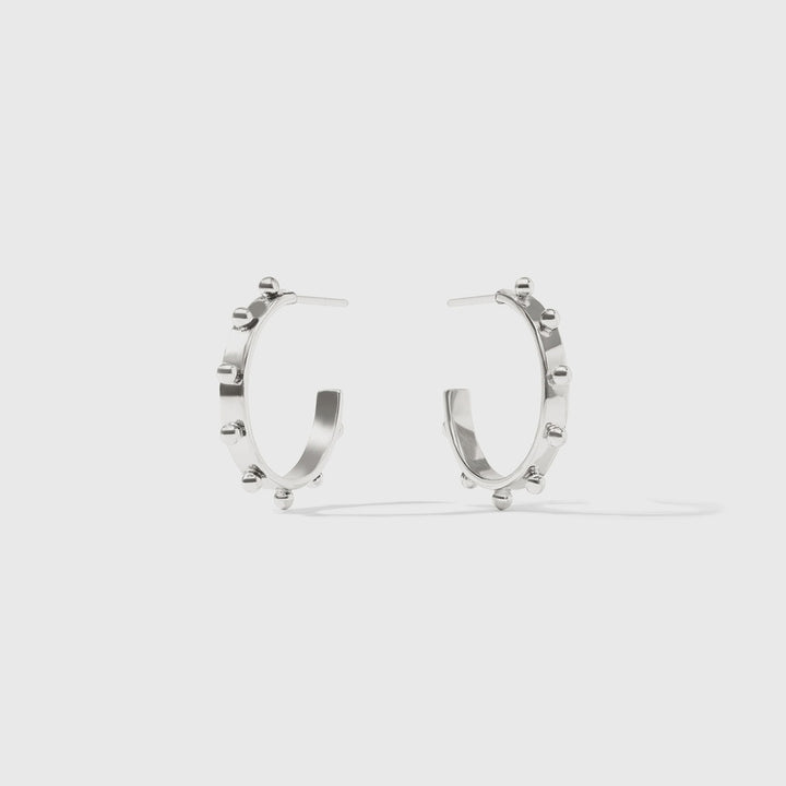 Silver earrings by Celine featuring a pair of open-hoop studs adorned with raised spherical accents and a high-shine polished finish against a neutral studio background