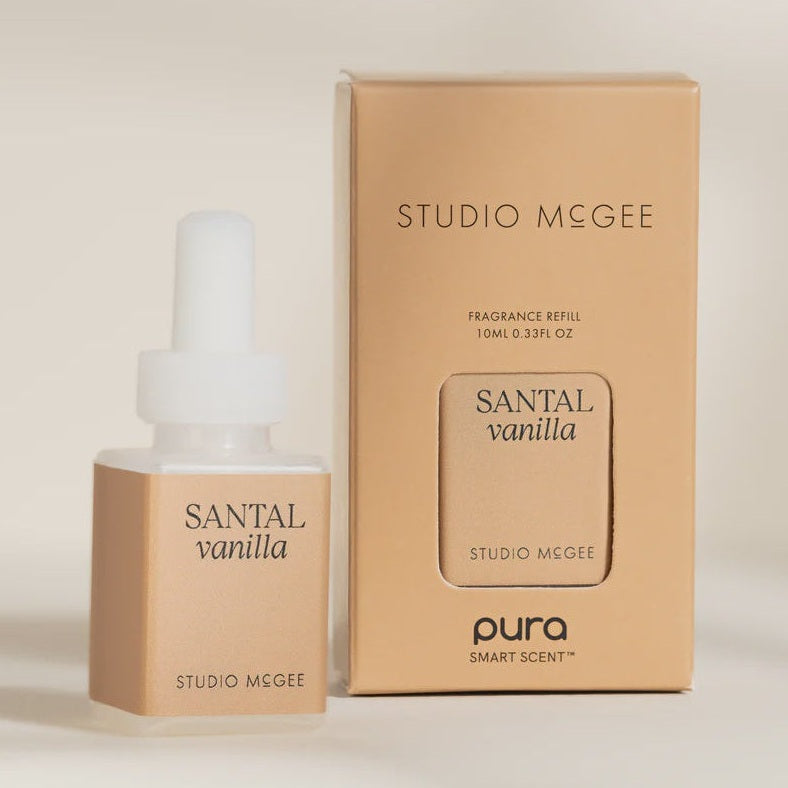 Digital product photograph for Studio McGee and Pura depicts a Santal Vanilla fragrance refill vial and its tan packaging box on a neutral surface, highlighting the Pura Smart Scent logo, minimalist black serif typography, and a frosted white cap