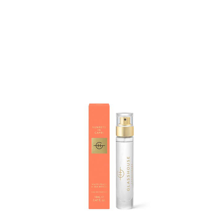 Product photography of Glasshouse Fragrances Sunsets in Capri Eau de Parfum featuring its vibrant orange-peach box and a slender clear glass travel vial with a gold atomizer cap