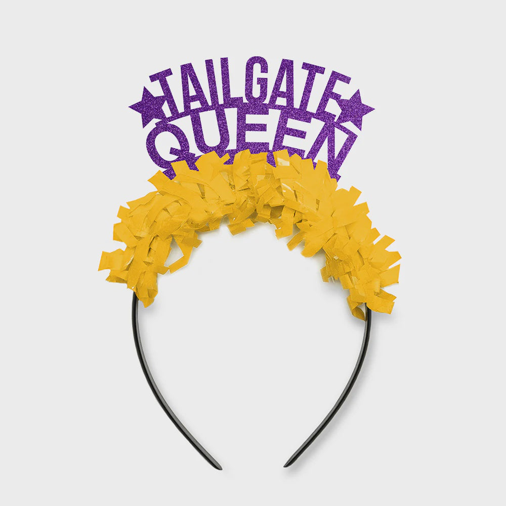 Product photograph of a festive Tailgate Queen headband featuring sparkling purple glitter lettering, two decorative stars, and a thick yellow paper fringe against a neutral gray backdrop