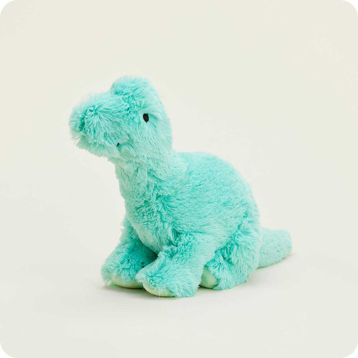 Stuffed toy by Jellycat of a mint green plush brontosaurus sitting in a studio setting with shaggy aqua-colored fur, small black bead eyes, and soft rounded feet