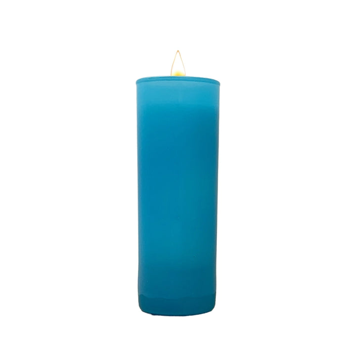 Studio photograph of a tall glass-encased prayer candle featuring vibrant turquoise blue wax and a single small yellow flame centered on a clean white background