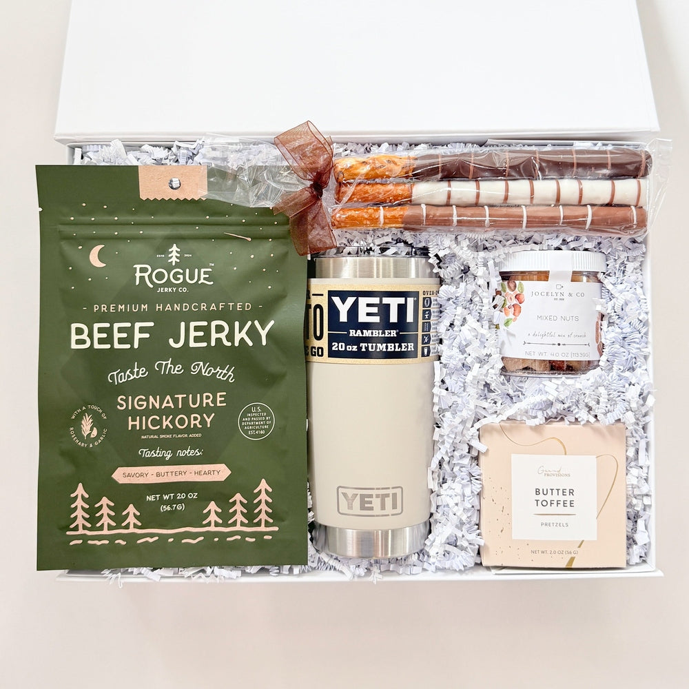Gift set with beef jerky, YETI mug, and other items in a clear box.